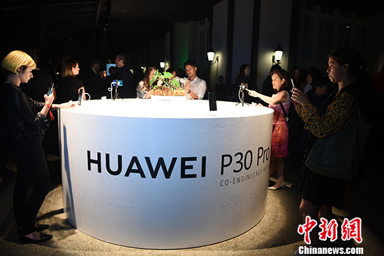 图为与会嘉宾现场体验华为P30系列高端手机。 /p中新社记者 莫成雄 摄